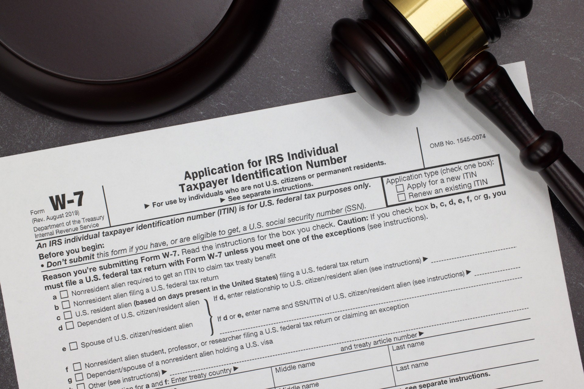 W-7 Application for IRS Taxpayer ID Number legal form with gavel and block on slate desktop