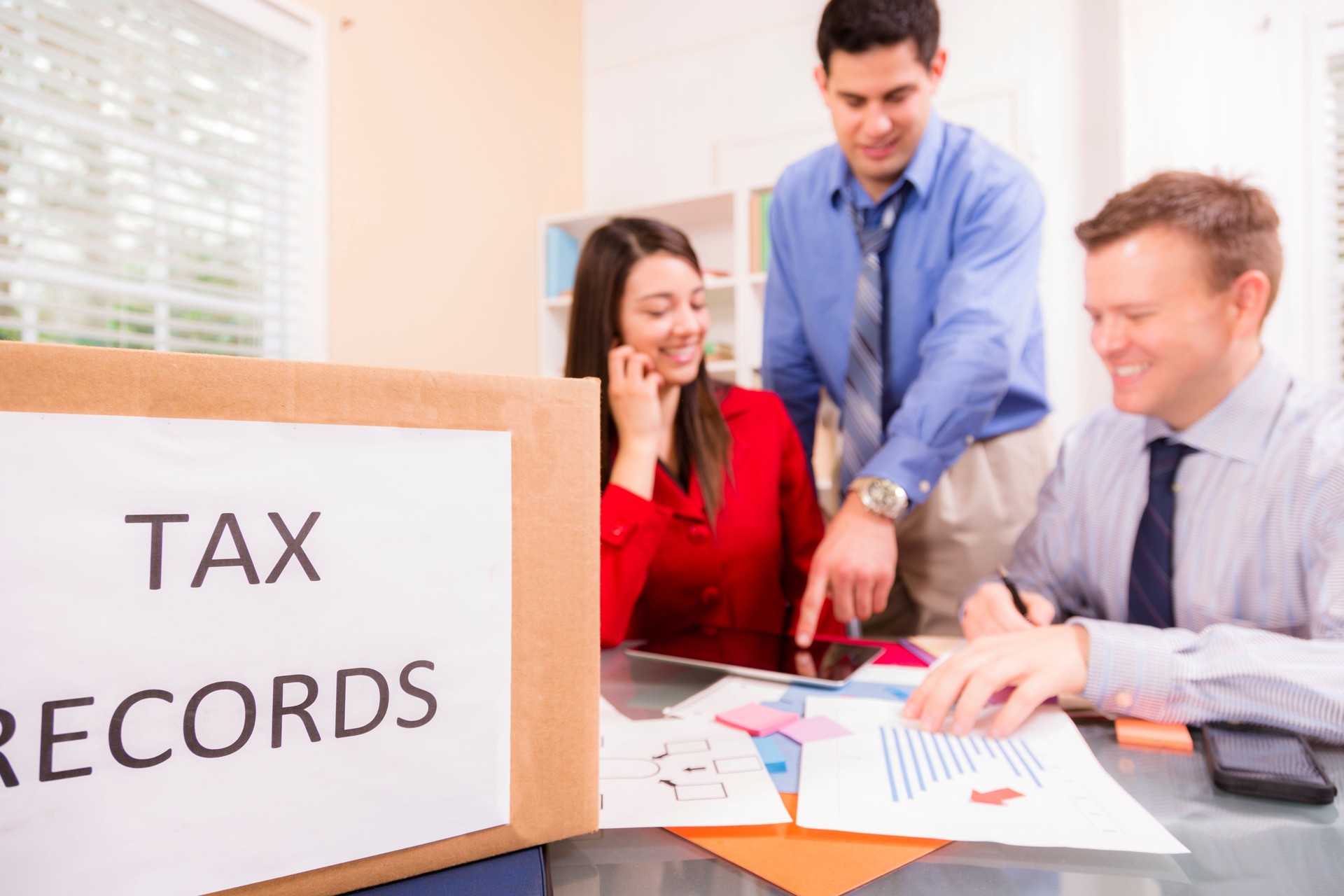 Accountants collaborate on income tax returns. Box foreground.