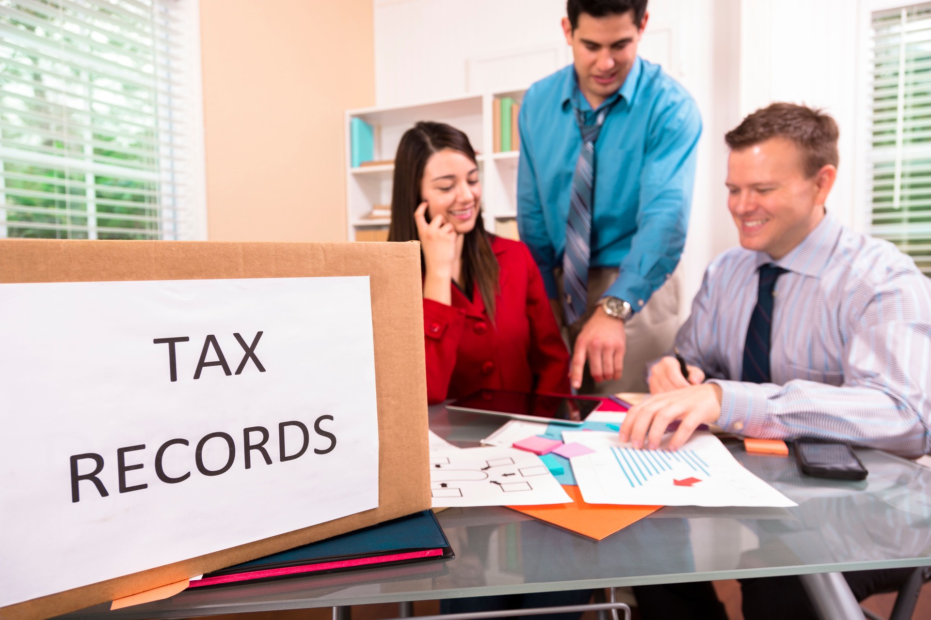 Accountants collaborate on income tax returns. Box foreground.